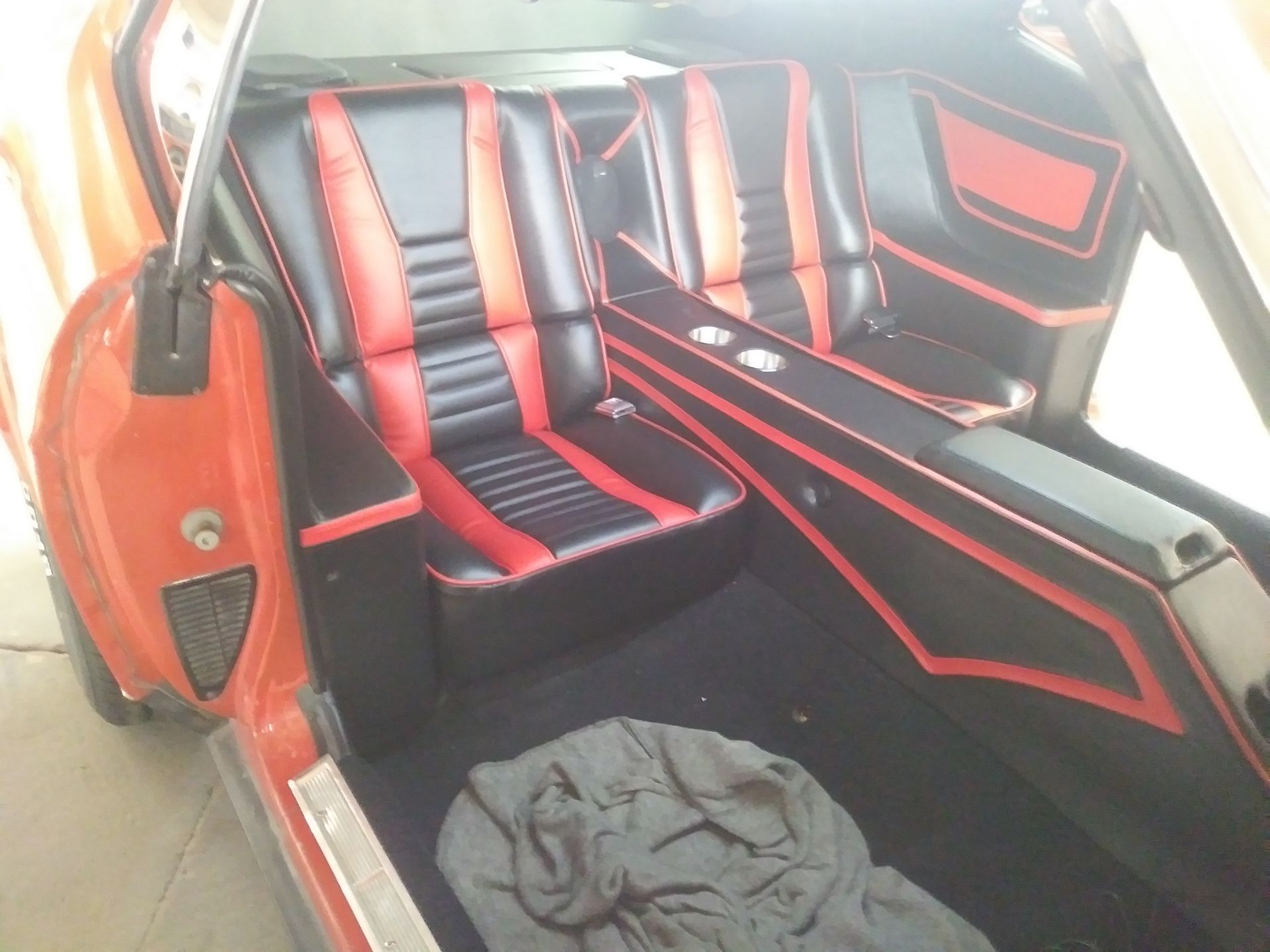 Custom red-and-black car interior with two bucket seats and a center console; gray cloth on the floor.