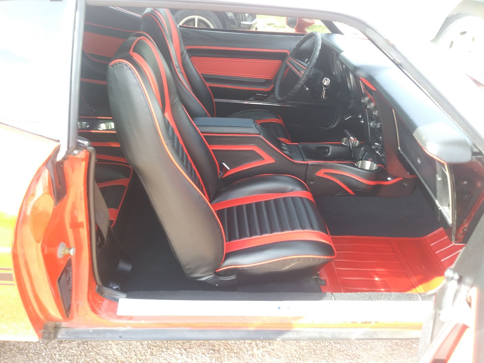 Car interior with black and red seats and trim, viewed through the open door.