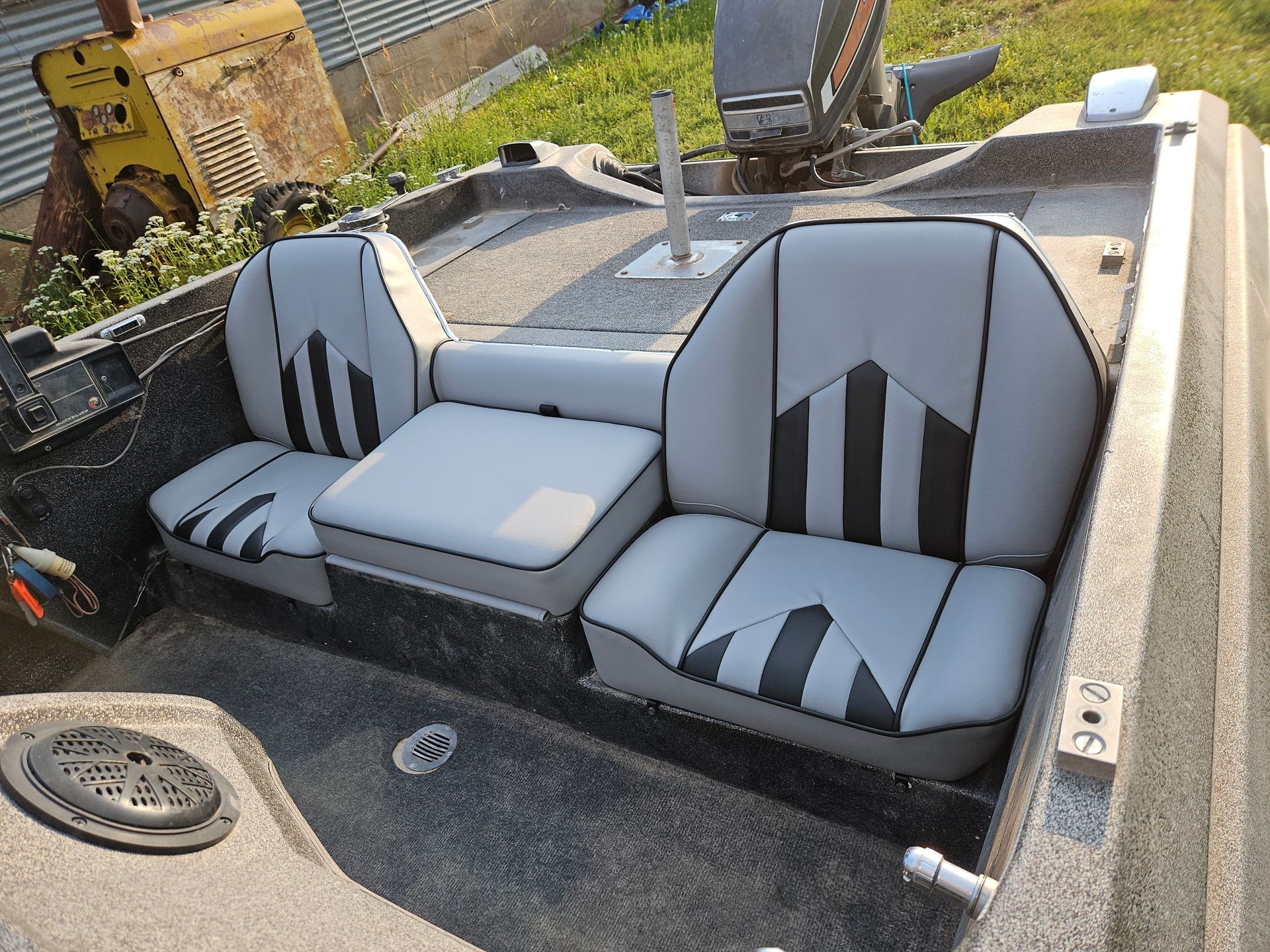 Boat interior with gray-and-black striped seats and a central console in a small open boat