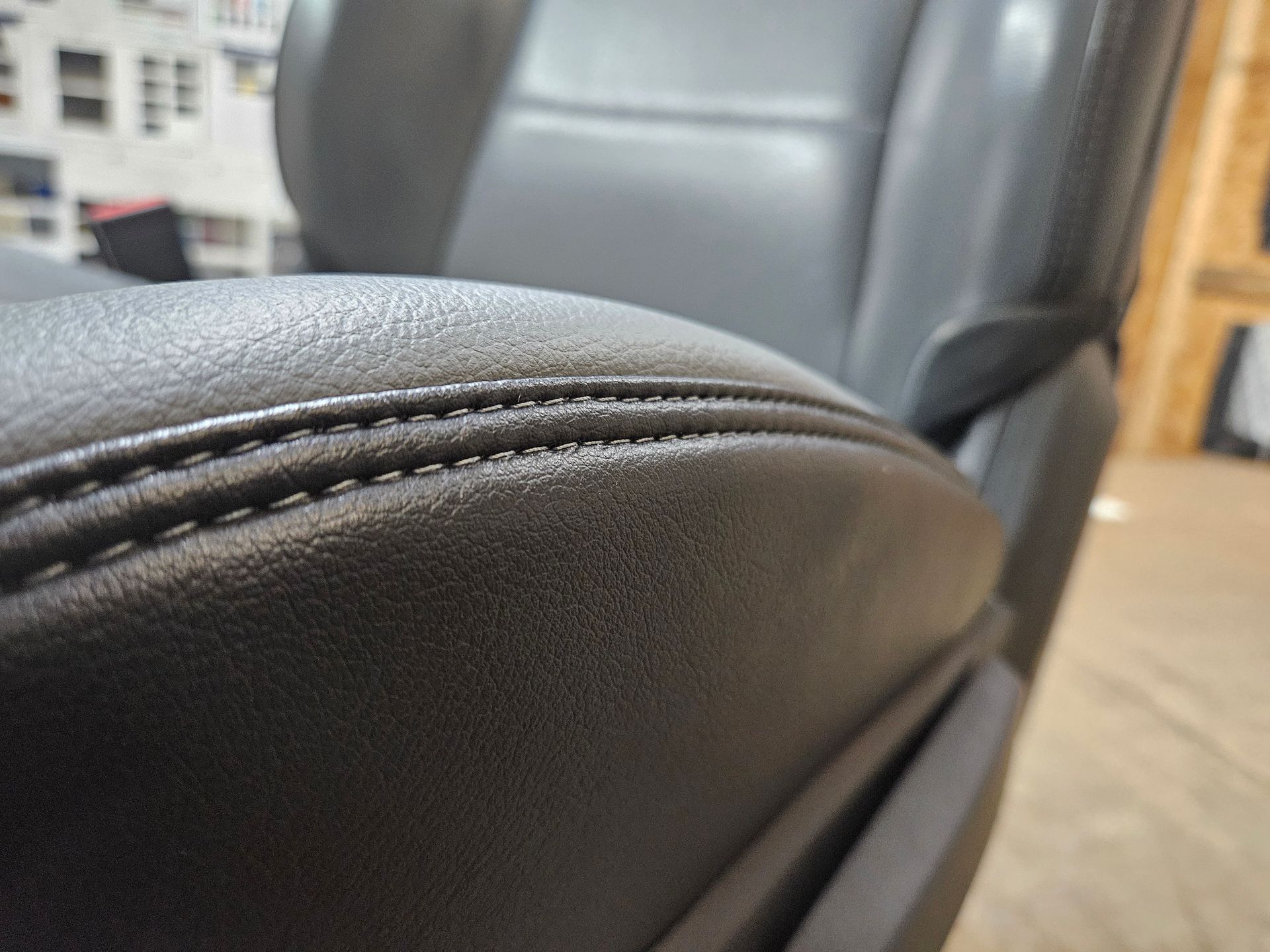 Close-up of a black leather chair armrest with visible stitching