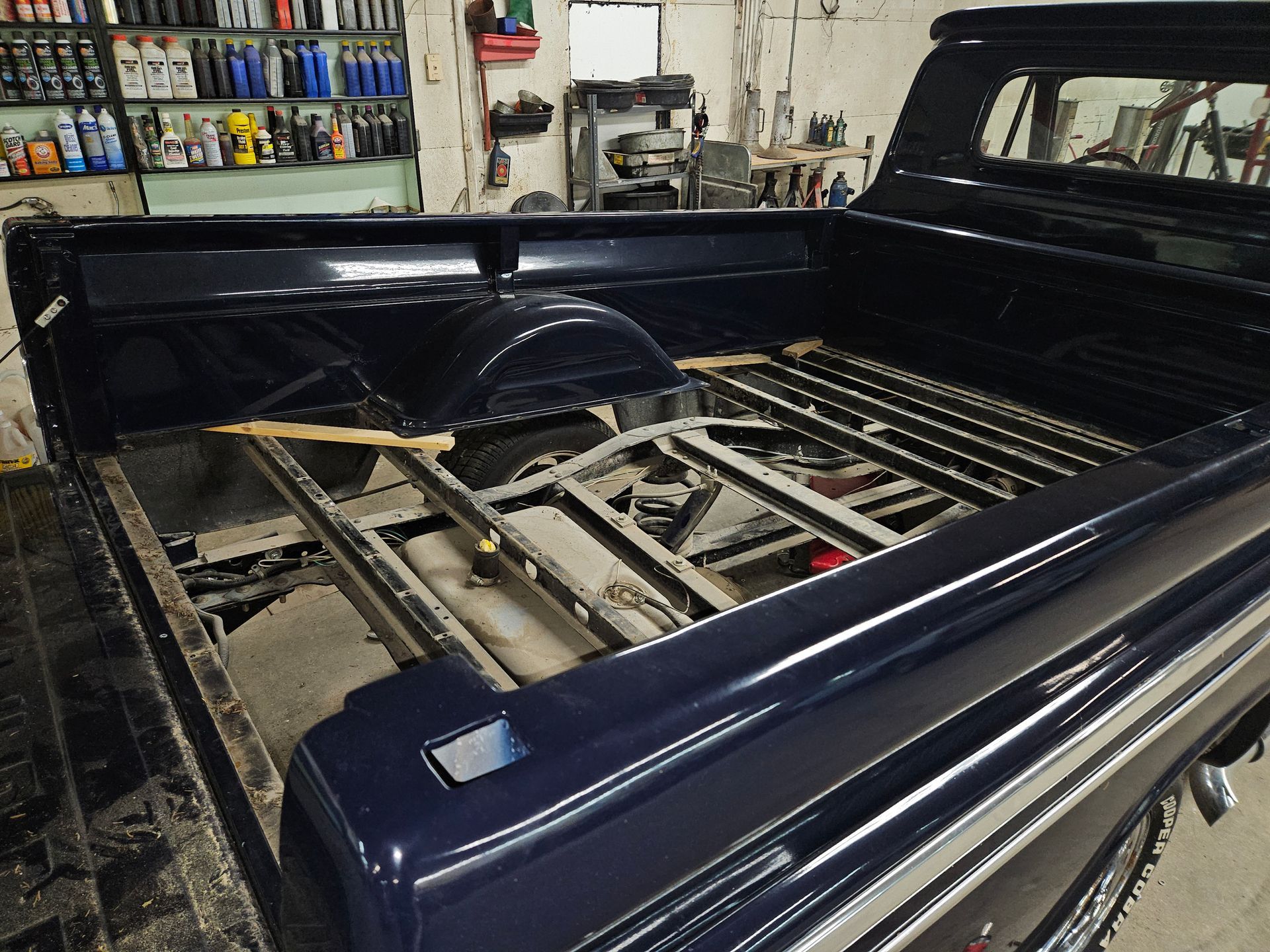 Pickup truck bed with exposed metal frame and components in a garage workshop