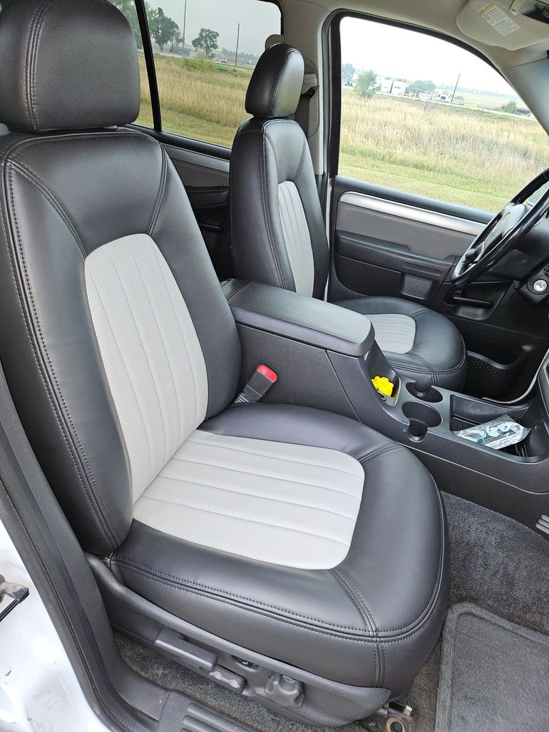 Front seats of a car interior with black and gray leather upholstery and center console.