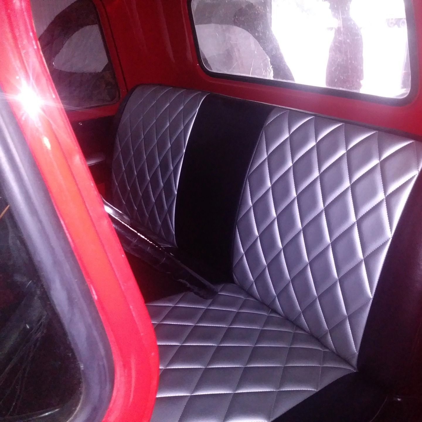Red car interior with black diamond-stitched seats and red trim viewed through an open door