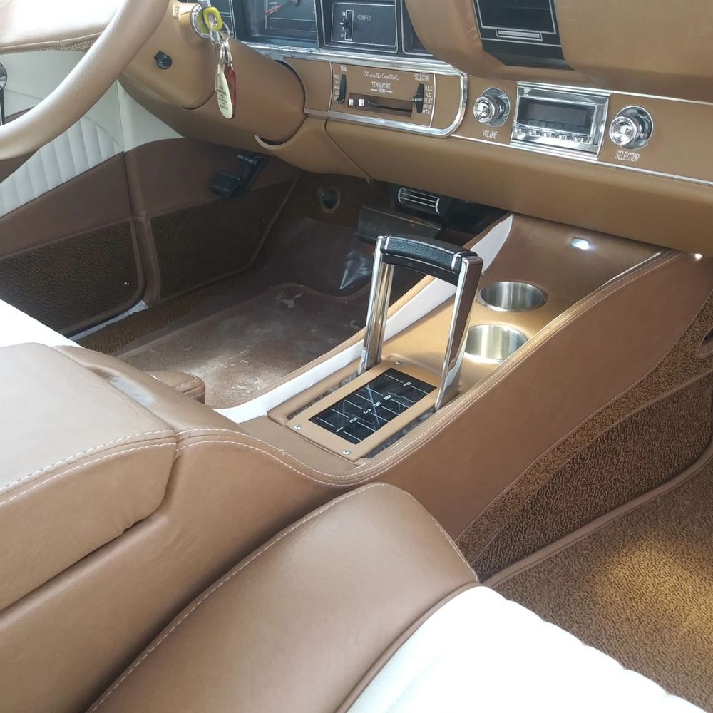 Vintage car interior with tan leather seats and a chrome center console shifter