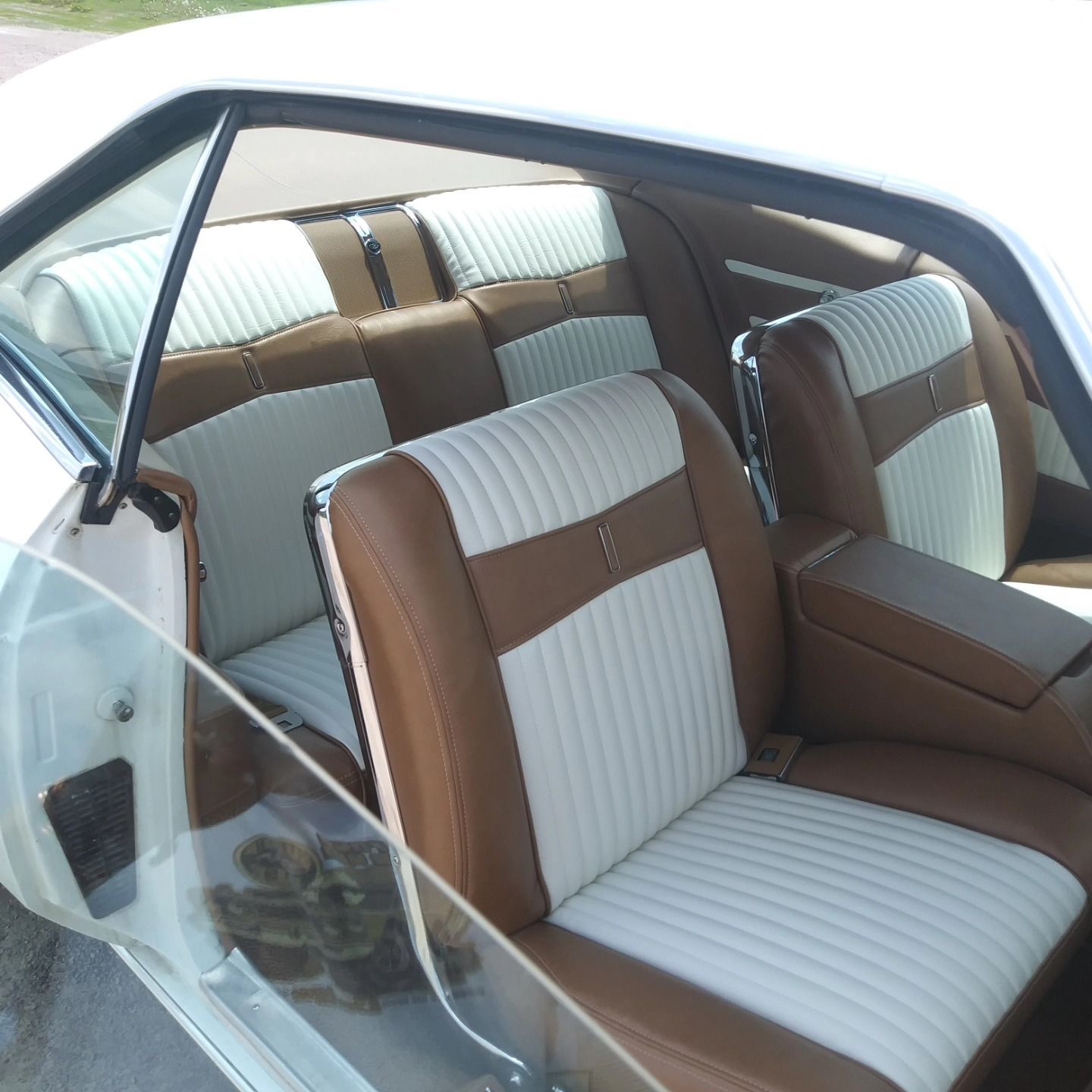 Vintage car interior with white and brown striped seats and a clear plastic side window