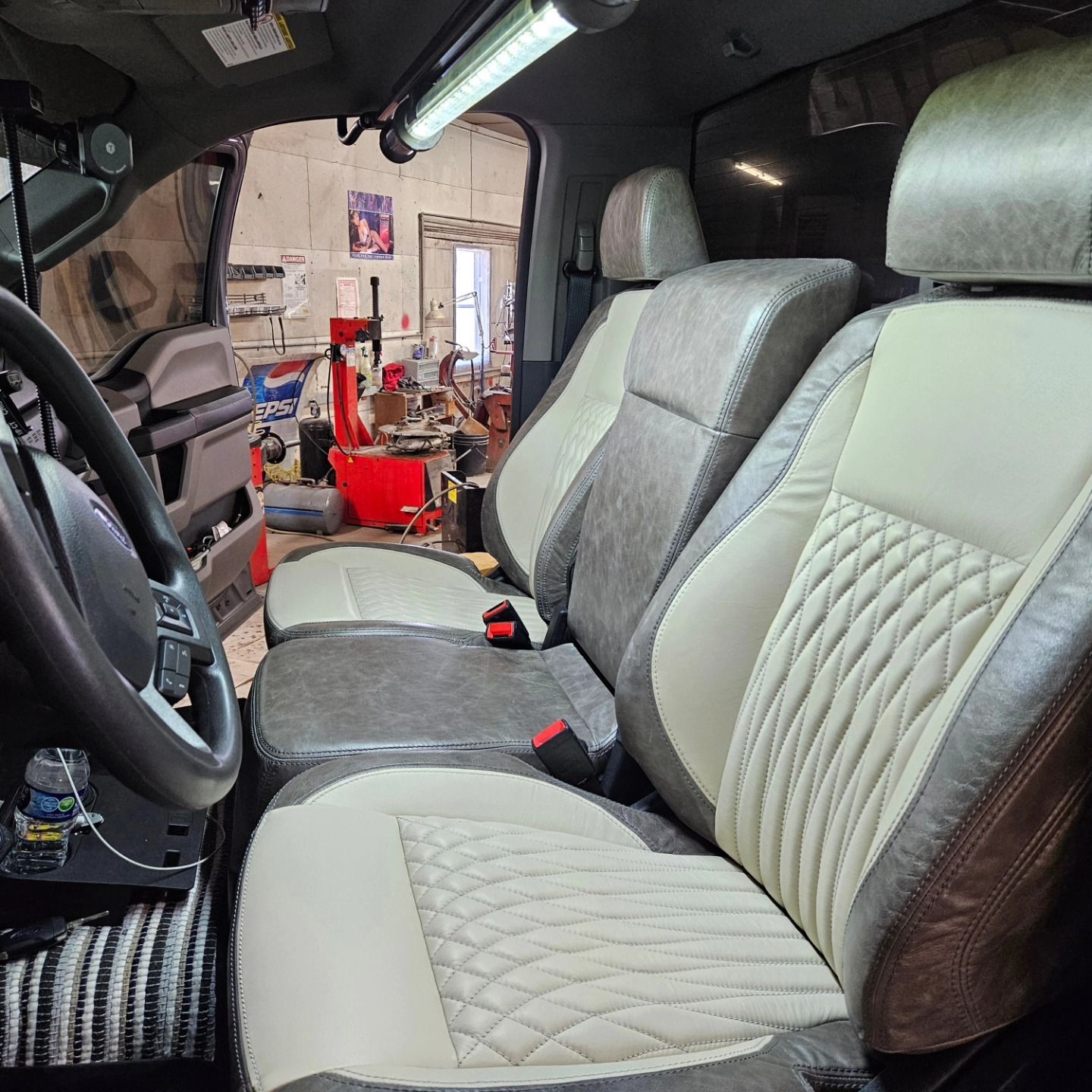 Modern truck interior with gray-and-white quilted seats and steering wheel, viewed from the driver’s side