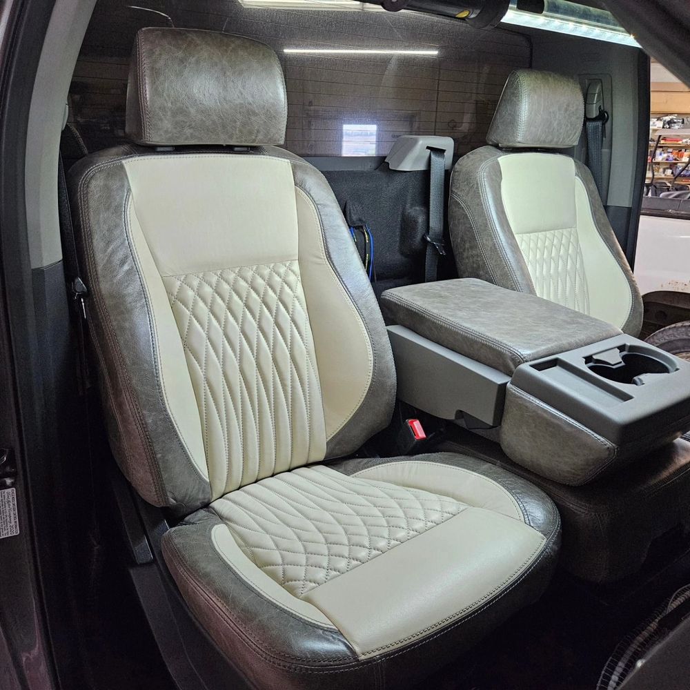 Luxury car interior with two beige quilted front seats and a center console