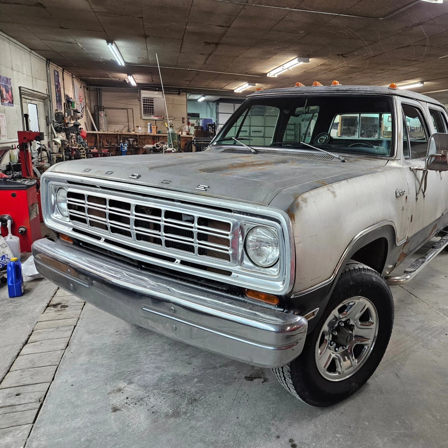 Vintage gray pickup truck in an auto shop garage, front view with chrome grille and headlights.