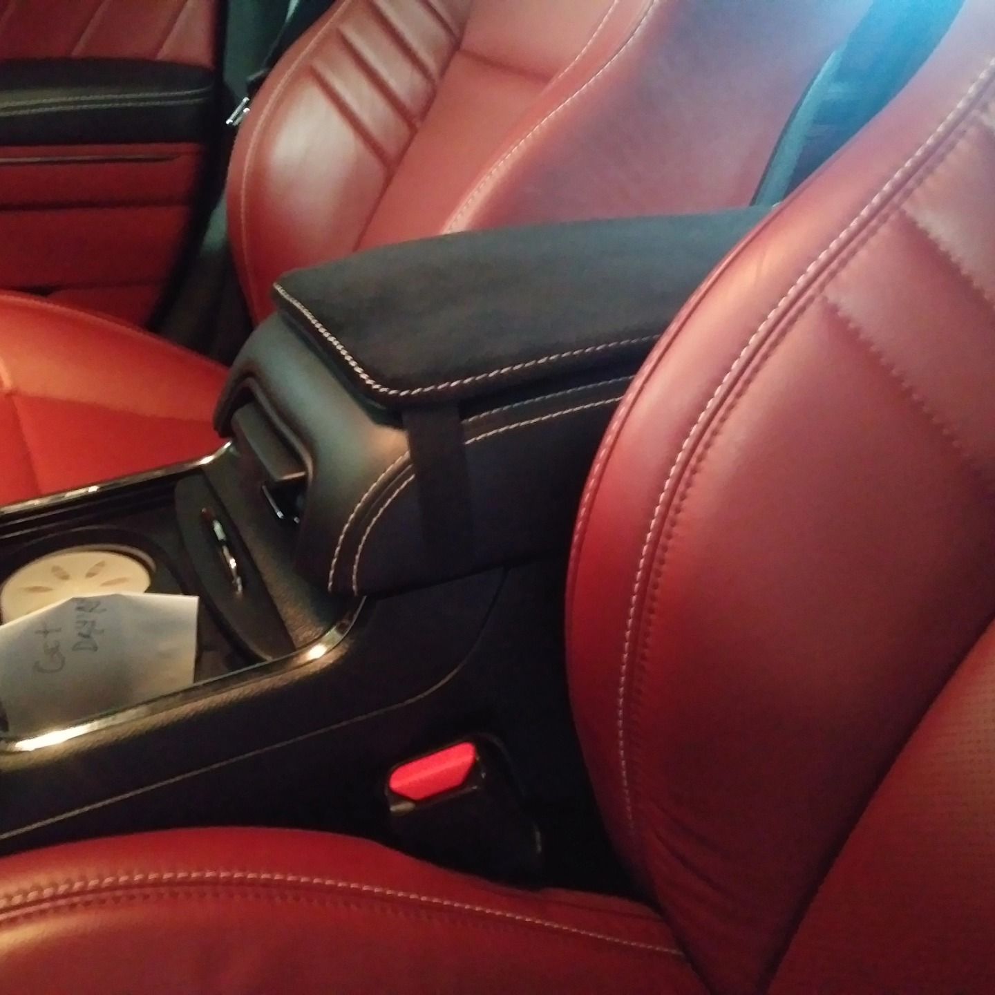 Red leather car interior with center console and black armrest, close-up view