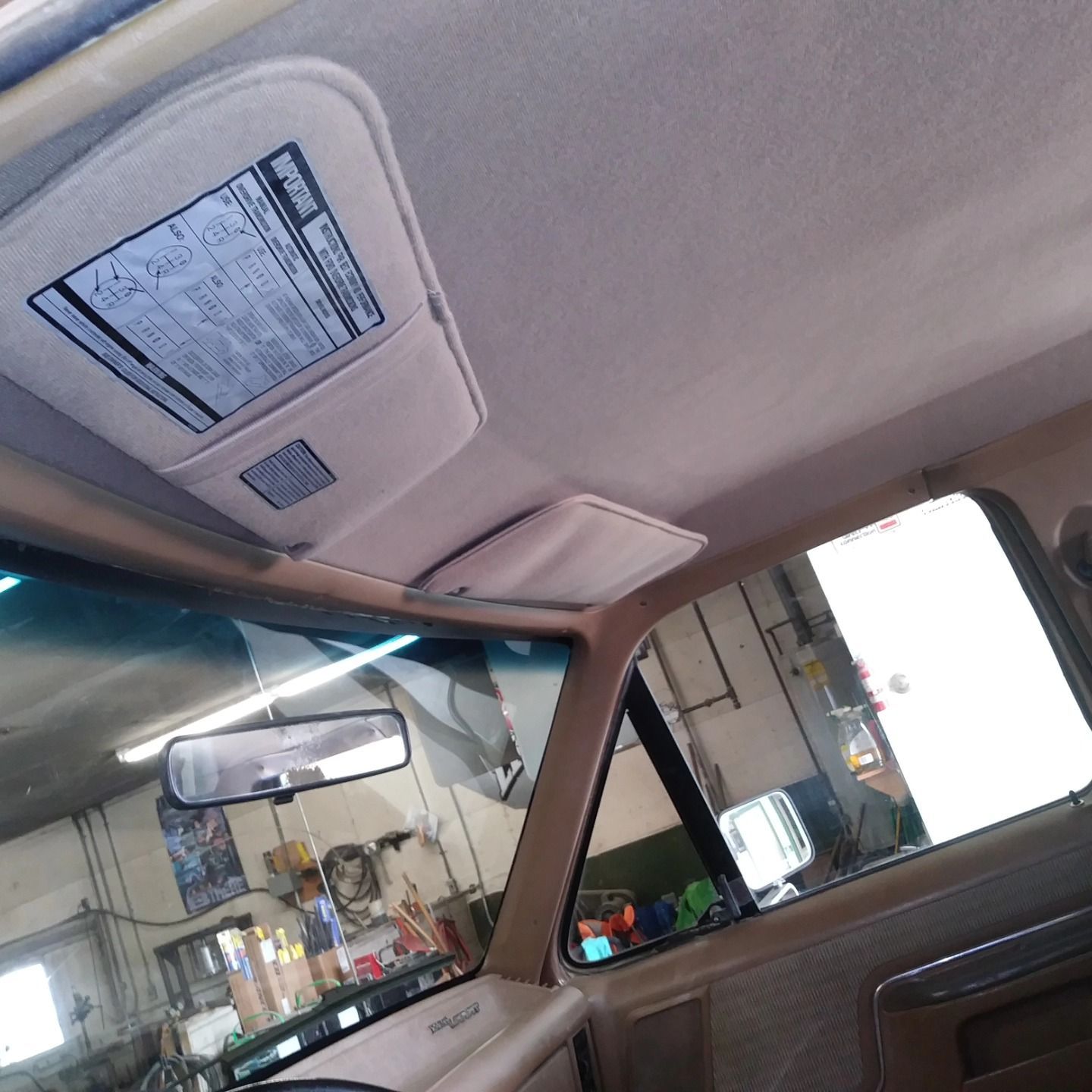 Car interior with sun visor, rearview mirror, and a view into a garage through the open door.