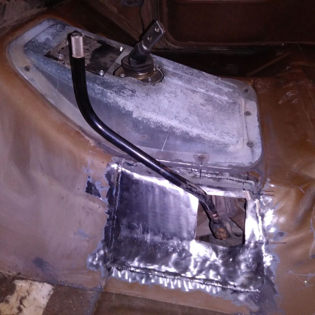 Metal hatch with a black cable and taped patch inside a brown utility compartment