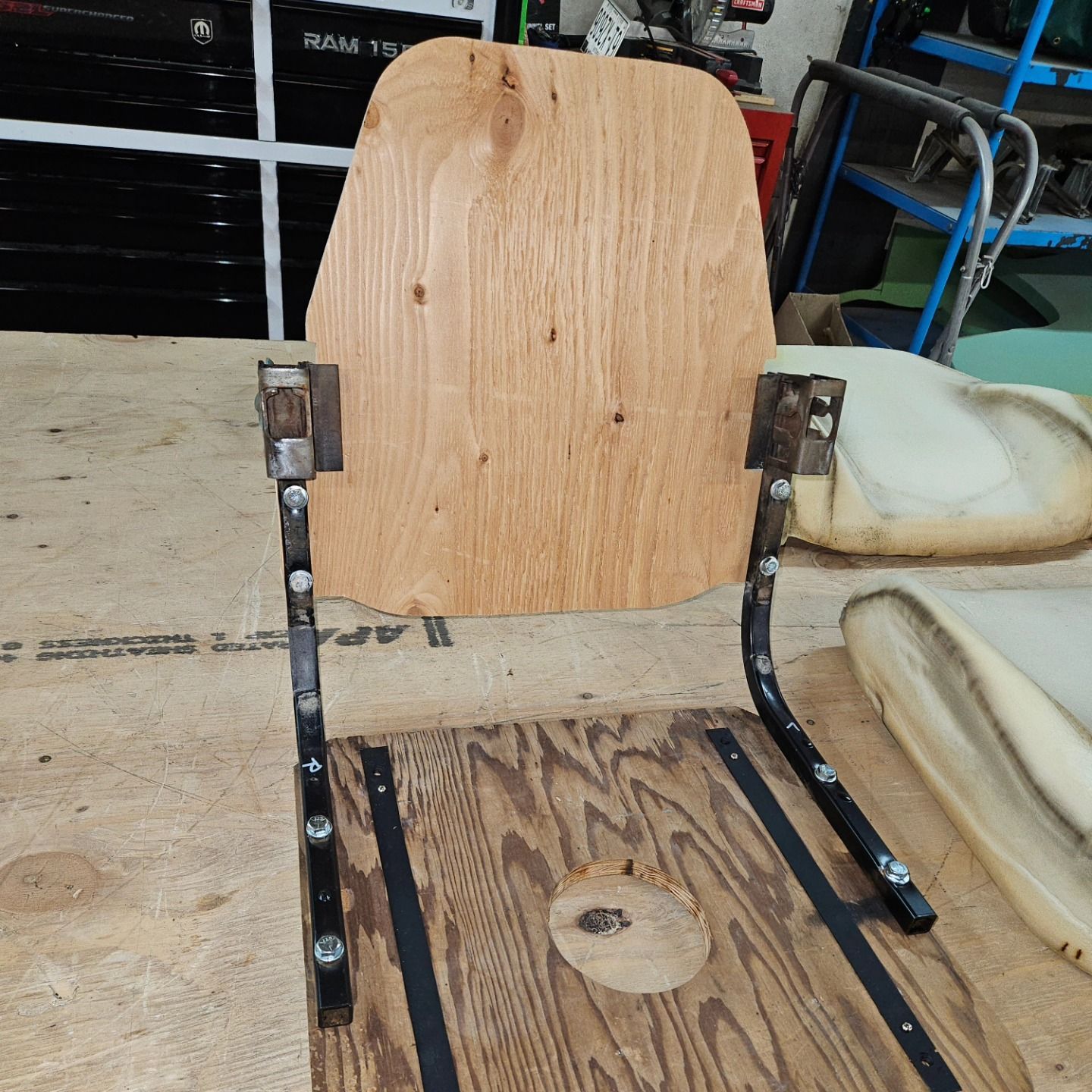 Wooden chair backrest on a workshop bench with metal brackets and arm supports.