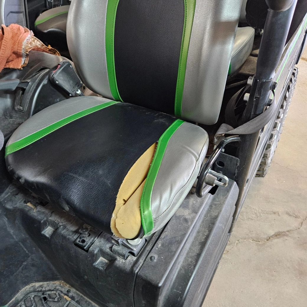 Damaged black and green car seat with torn cushion in a vehicle interior
