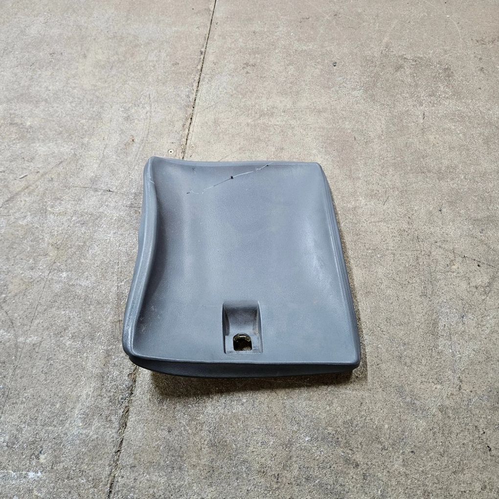 Black plastic car seat cushion on a concrete floor, with a small central opening near the front.