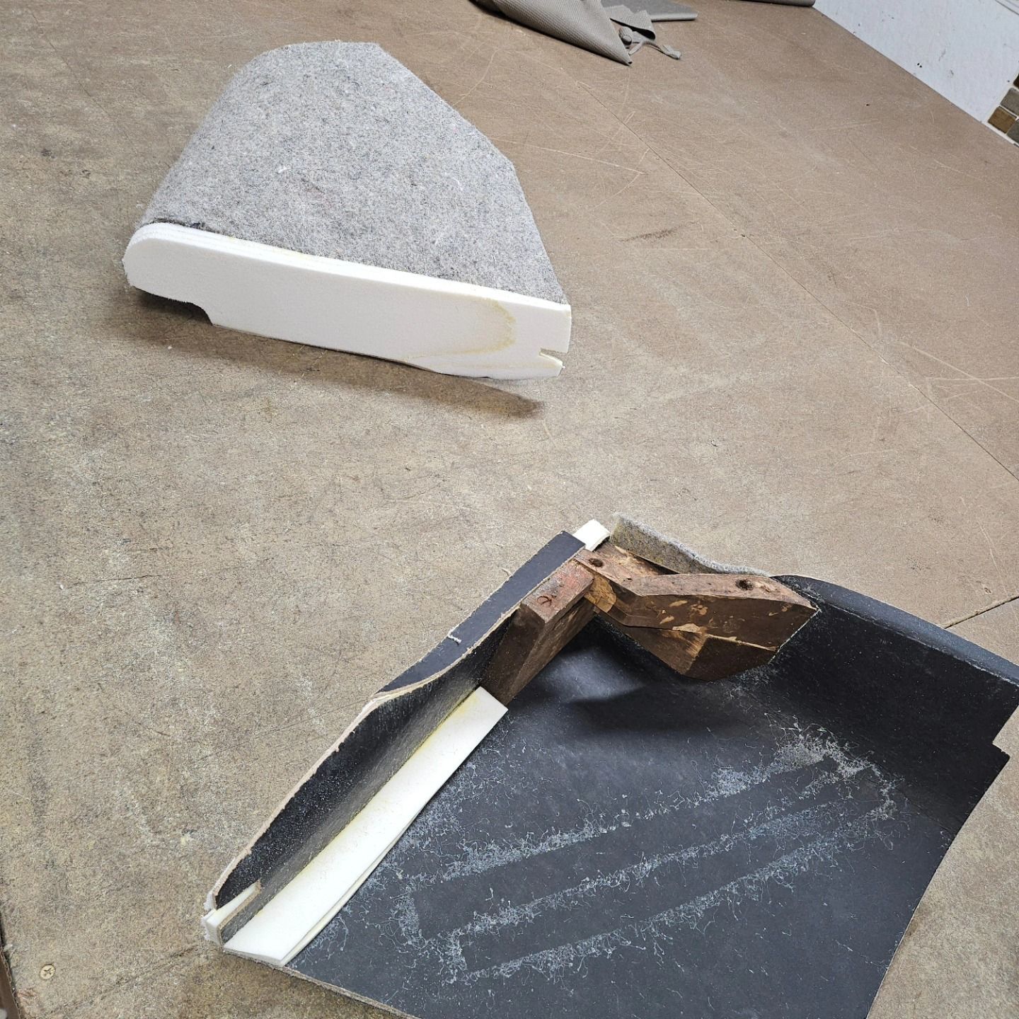 Broken gray and white foam pieces scattered on a concrete floor near a dark panel.