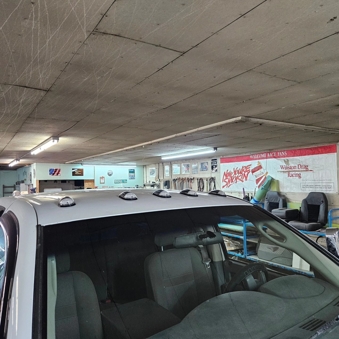 Indoor parking garage with a white SUV in the foreground and red signage on the wall.