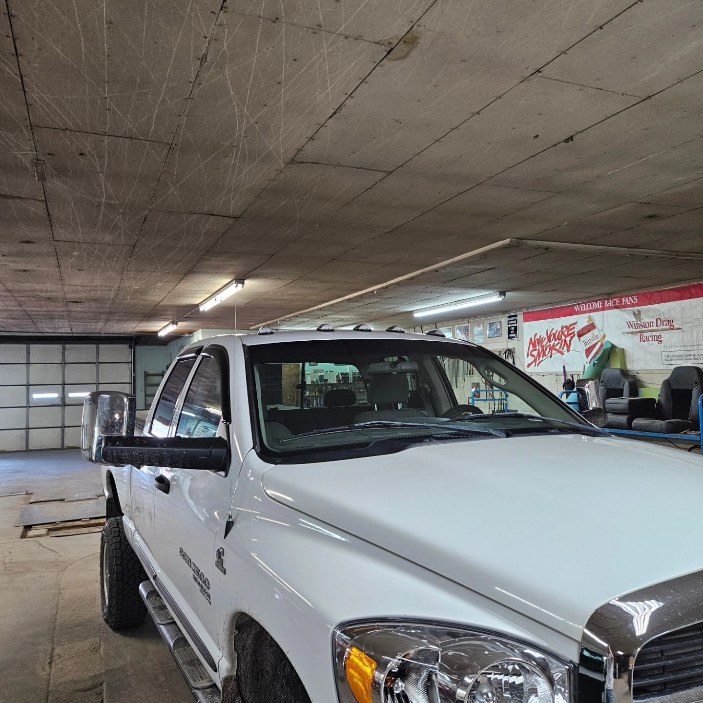 White pickup truck parked inside a garage, seen from the front side.