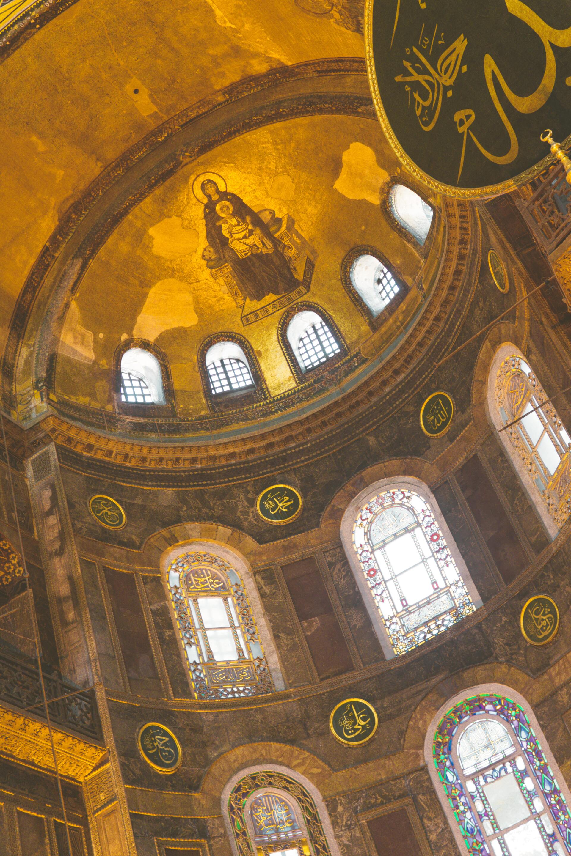 Looking up at the dome of a church with stained glass windows