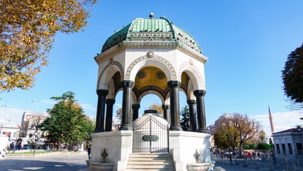 A large white building with a green dome and columns in a park.