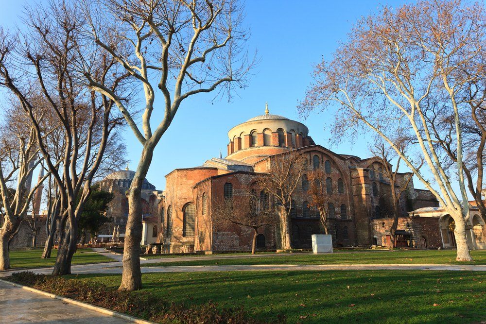 A large building with a dome is surrounded by trees in a park.