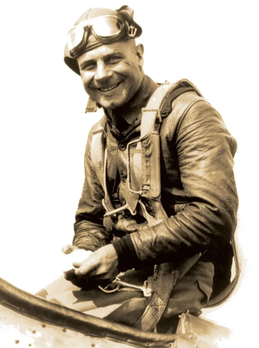 Smiling pilot in leather jacket and goggles.