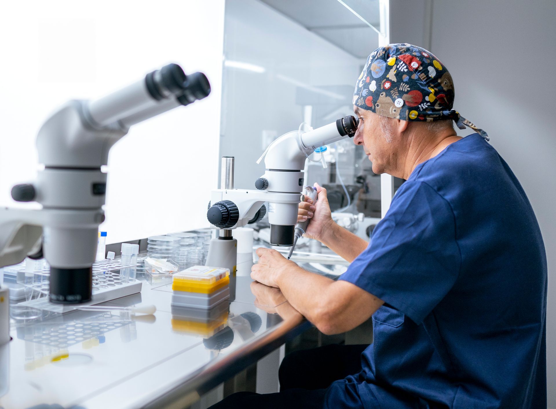 Doctor examining a patient's throat in a medical office. The doctor wears a white coat and pink gloves.