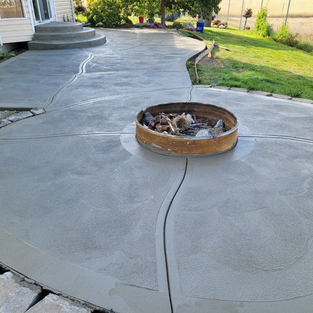 Concrete patio with fire pit, steps to a house, and a grassy backyard.