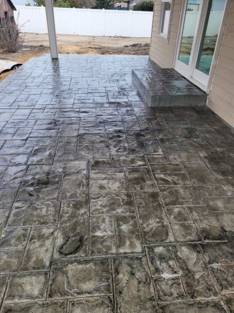 Stamped concrete patio with a brick pattern. Grey color. Outdoors.