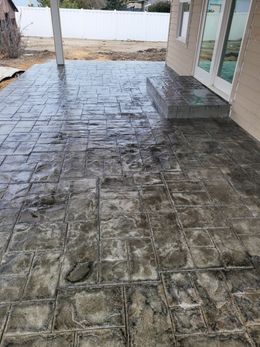 Stamped concrete patio with a brick pattern. Grey color. Outdoors.