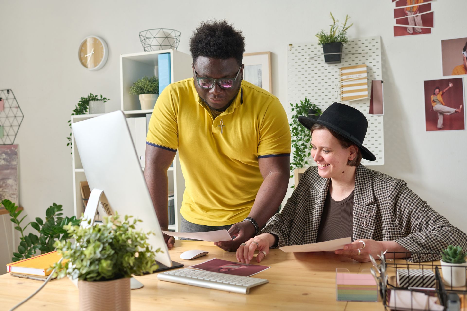Two people looking at a computer monitor and papers at a desk in an office.