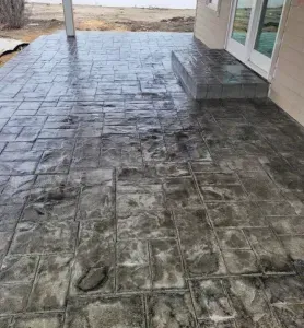 Stamped concrete patio with a brick pattern. Grey color. Outdoors.