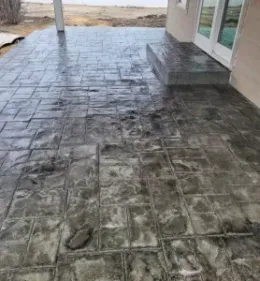 Stamped concrete patio with a brick pattern. Grey color. Outdoors.