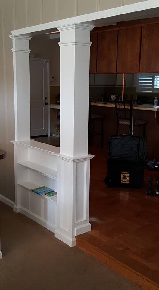 There is a shelf between the living room and the kitchen.