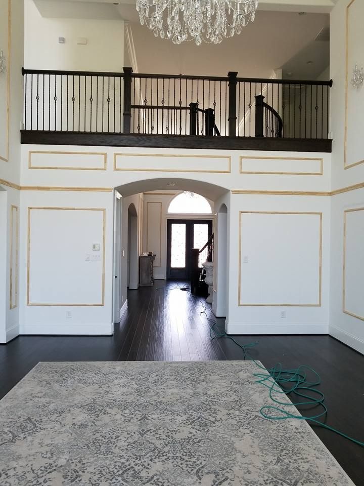A large empty room with a rug and a chandelier.