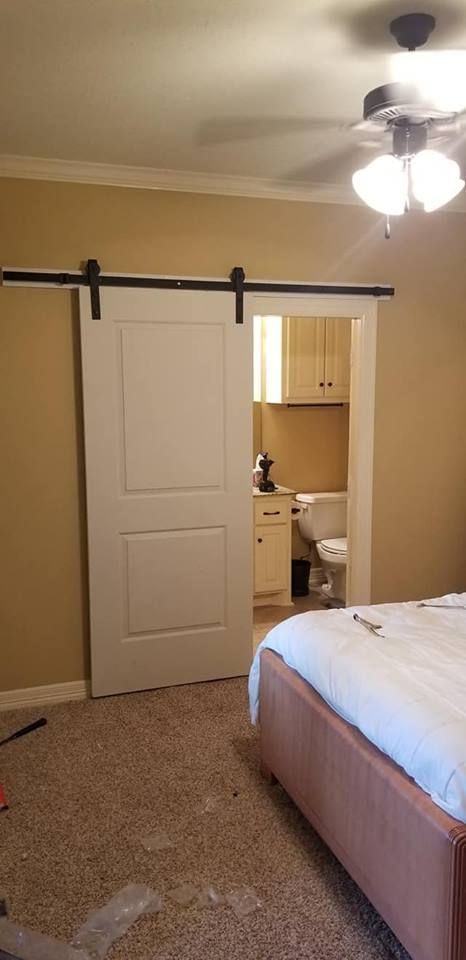 A bedroom with a sliding barn door leading to a bathroom.