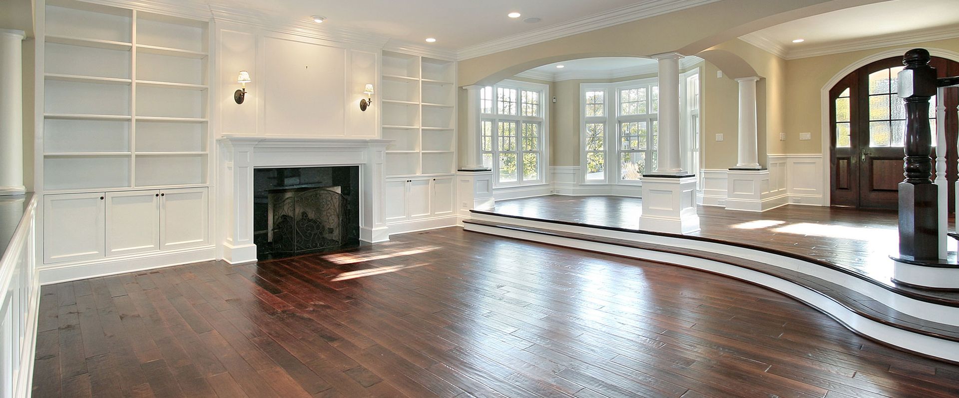 An empty living room with hardwood floors and a fireplace.