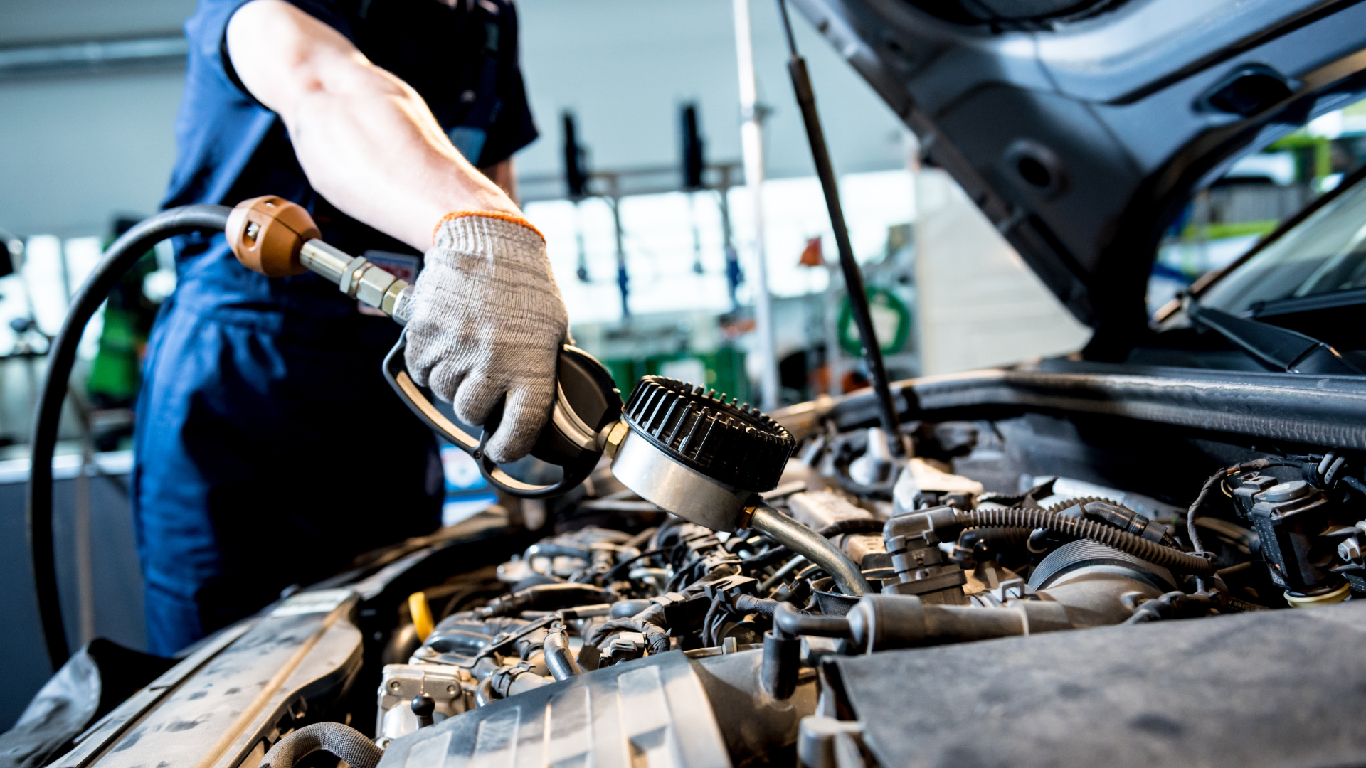 A man is working on the engine of a car in a garage.