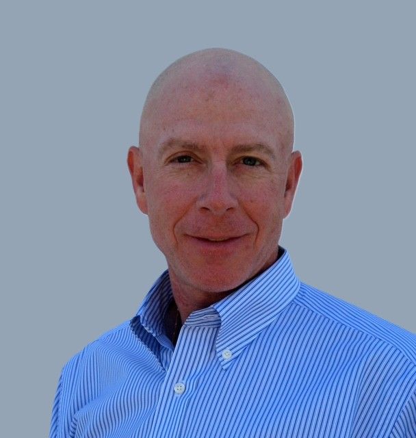 Woman with long dark hair smiles, wearing a black top.