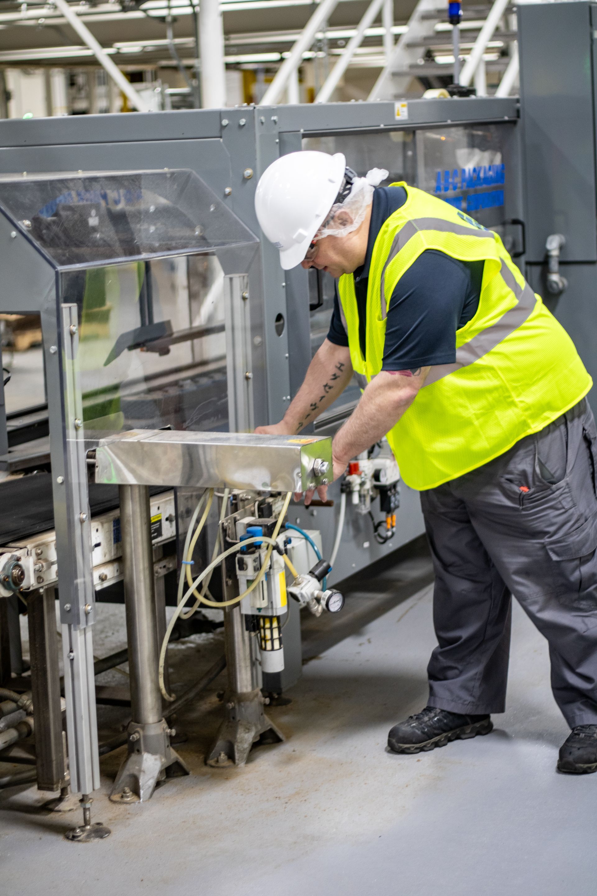 Person in safety gear inspecting machinery in a factory.
