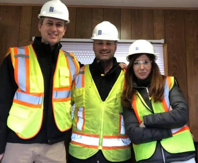 Three people in safety vests and hard hats stand next to a Kellogg's sign.