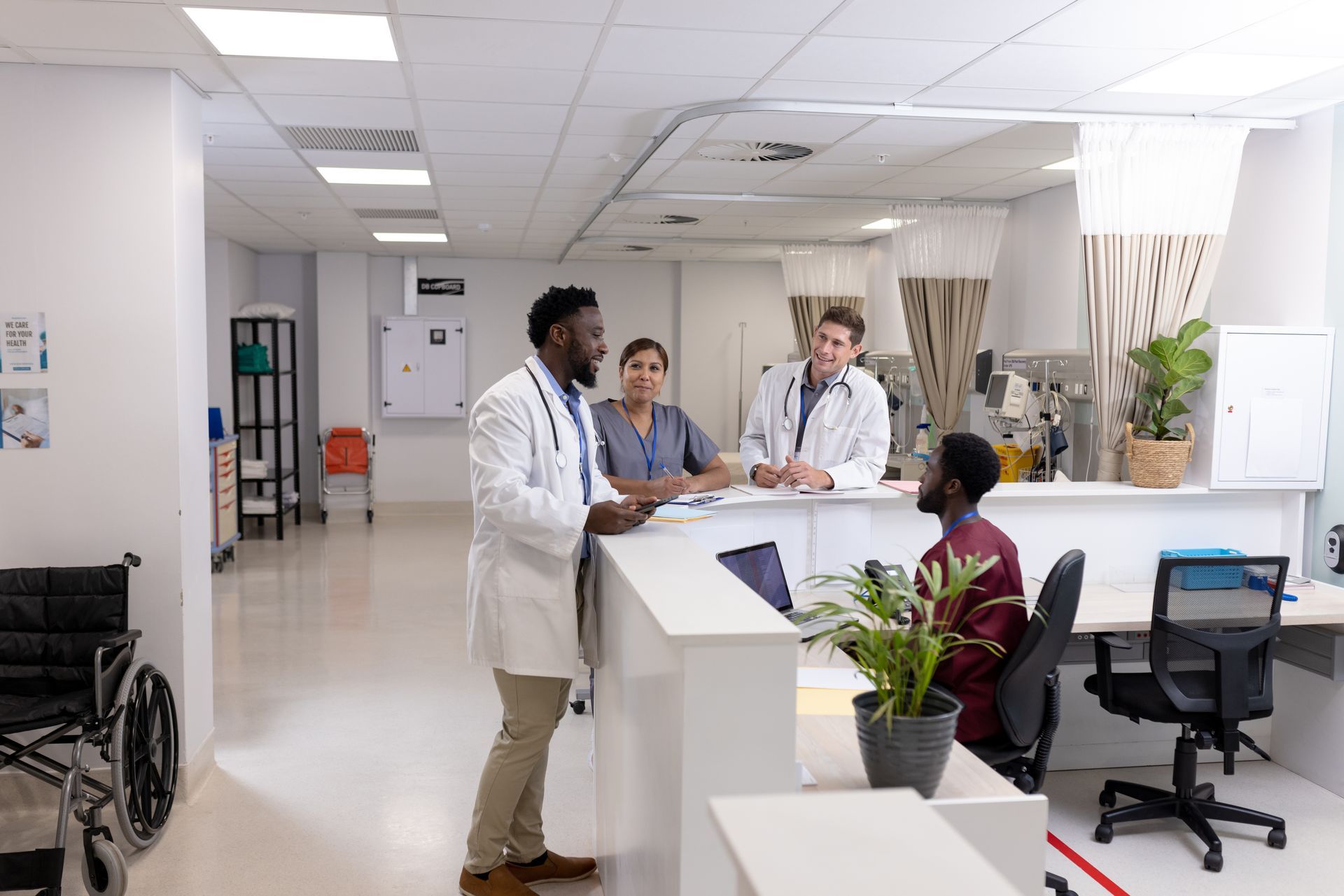Doctors and a nurse at a hospital reception desk talking to a patient. Brightly lit interior.