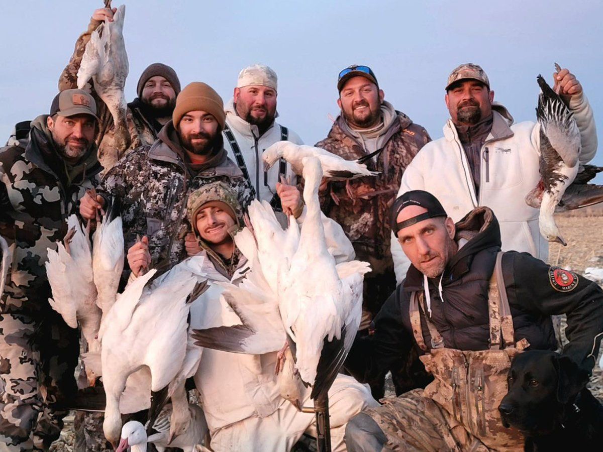 A group of men are posing for a picture with their birds.