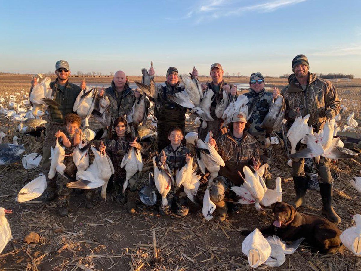 A group of hunters are posing for a picture with their birds.
