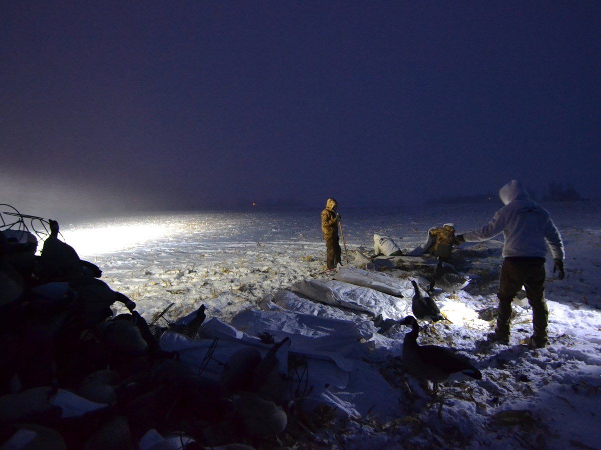 A group of people are standing in the snow at night