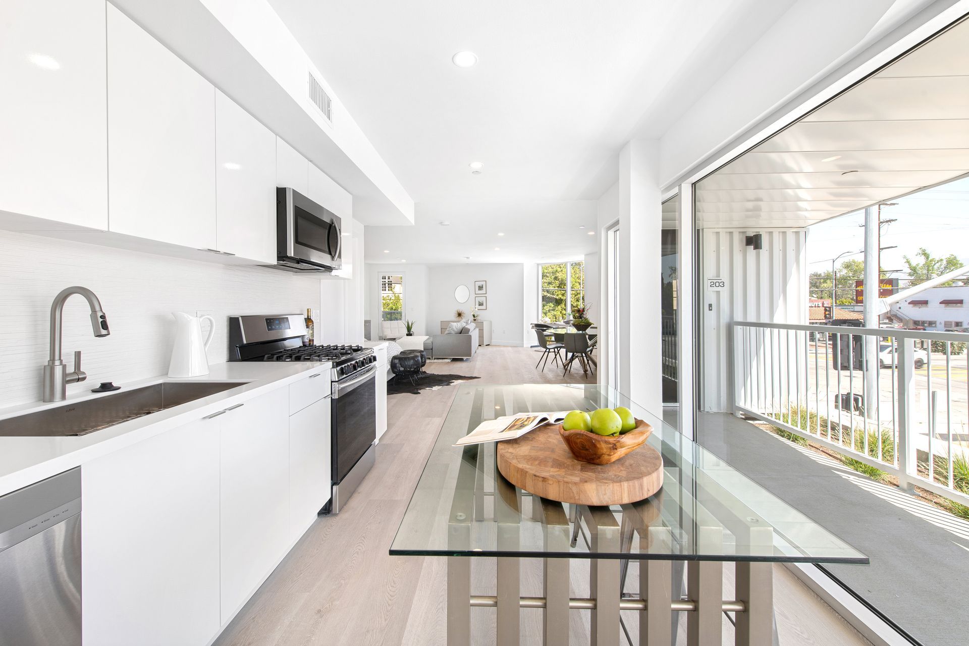 A kitchen with a glass table and a bowl of apples on it.