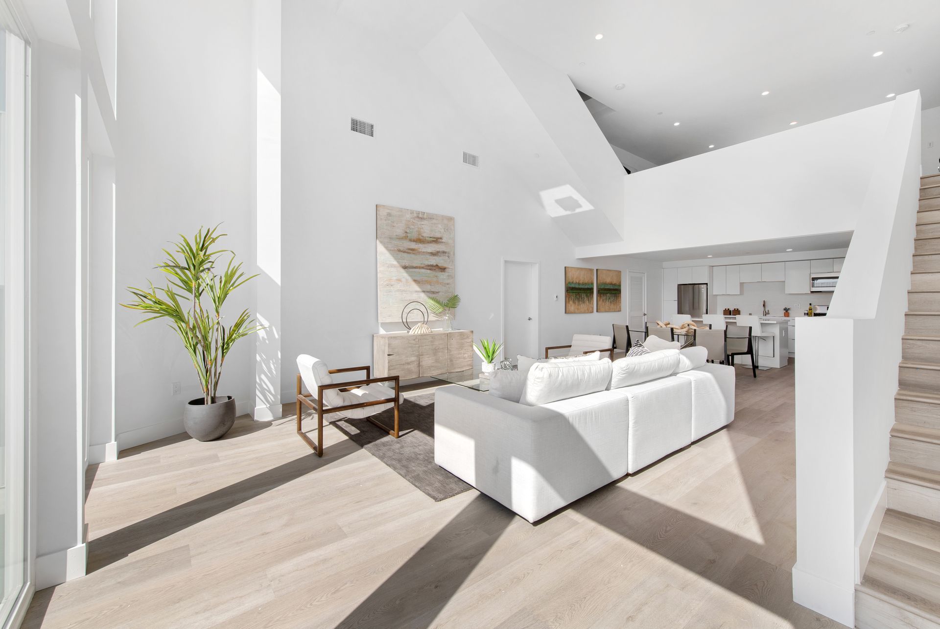 A living room with a white couch , chairs , and stairs.