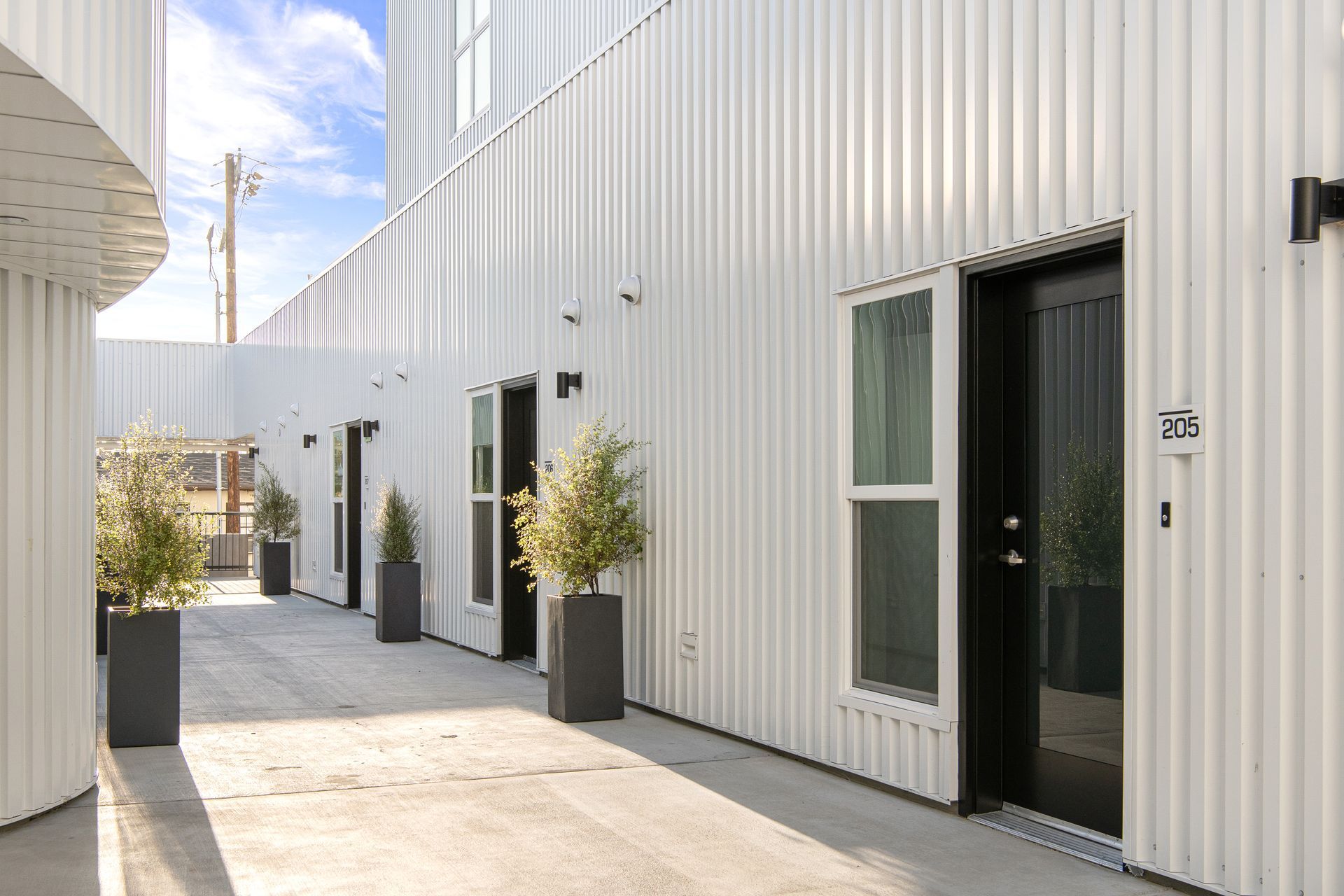 A white building with a black door and planters in front of it.