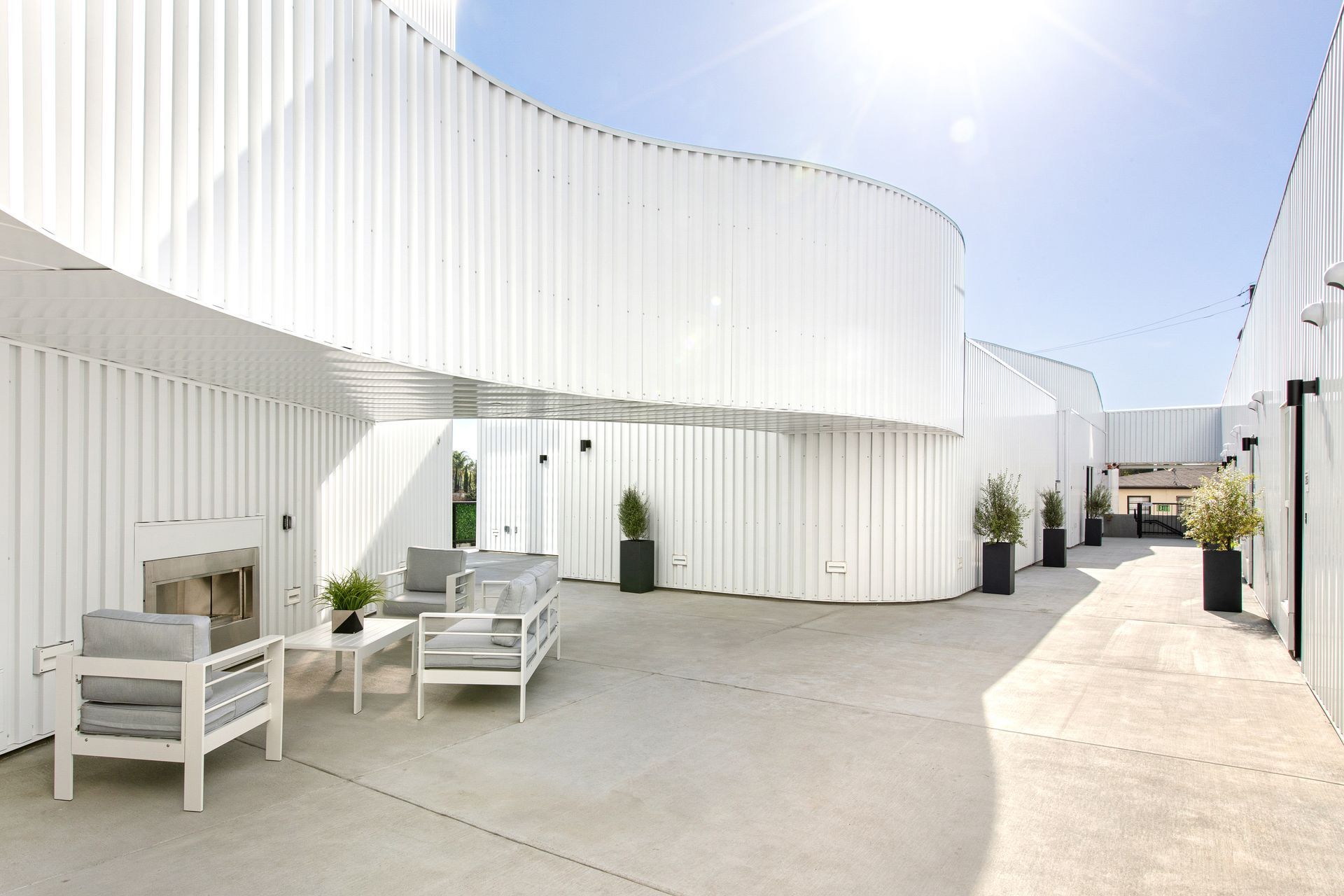 A white building with a patio area with chairs and a fireplace