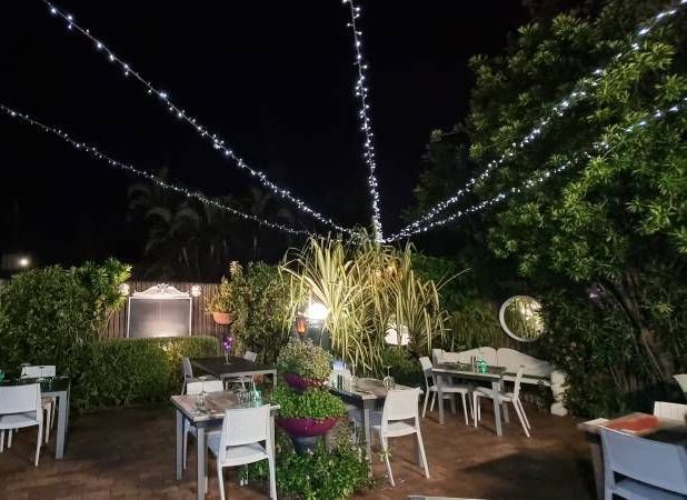 A Restaurant With Tables And Chairs On A Brick Patio — Wayne & Adele's Garden of Eating BYO Restaurant In South Townsville, QLD