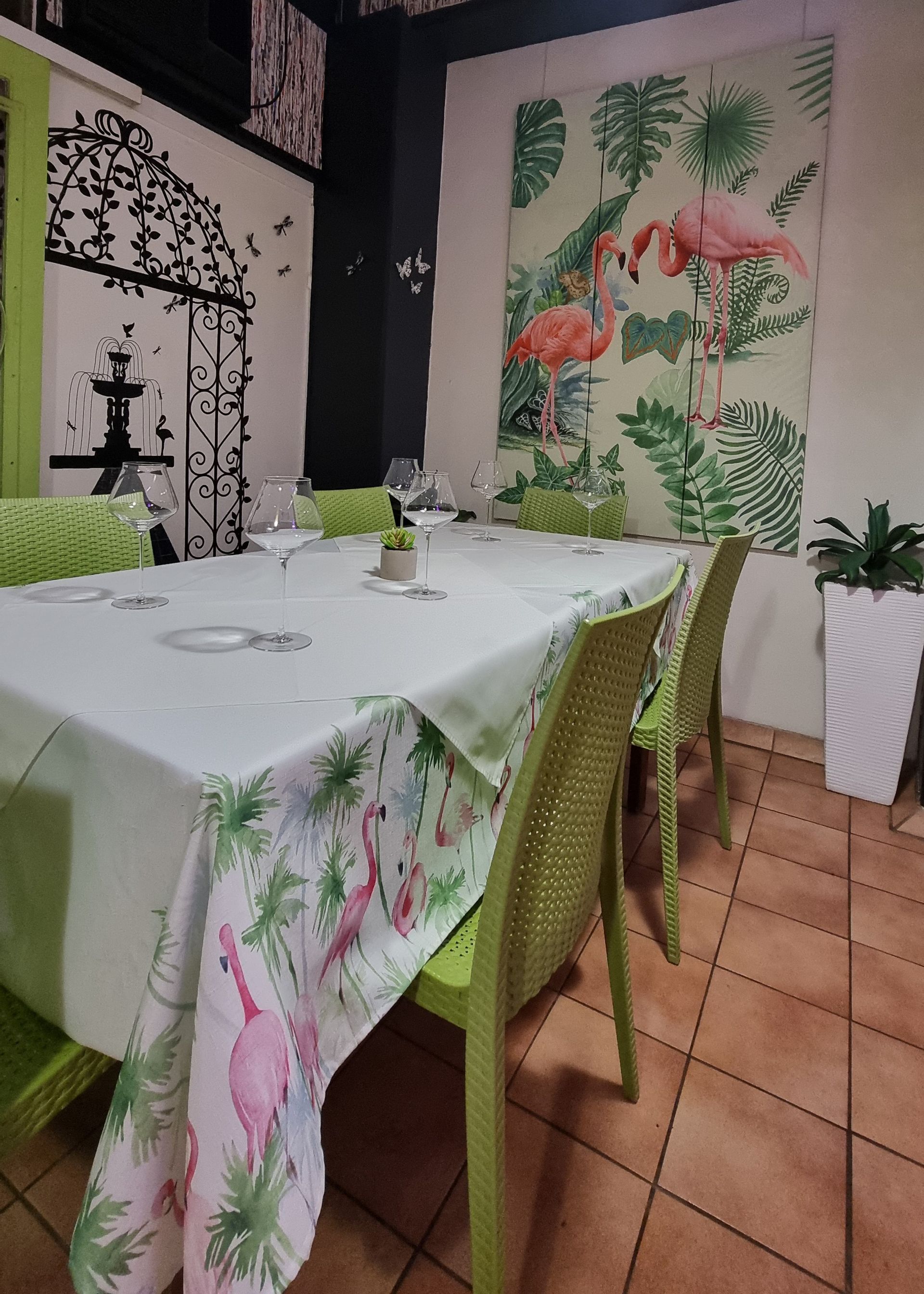 A dining room with a table and chairs and a painting of flamingos on the wall  — Wayne & Adele's Garden of Eating BYO Restaurant In South Townsville, QLD